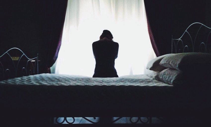 Woman sitting on a bed in a dimly lit room