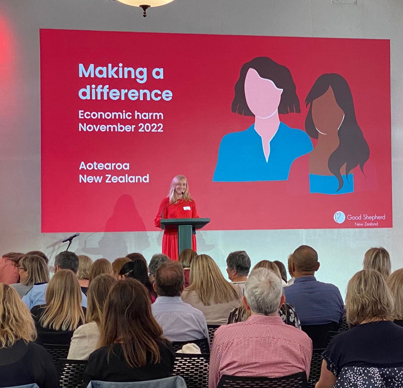 Woman smiling and presenting at a conference.